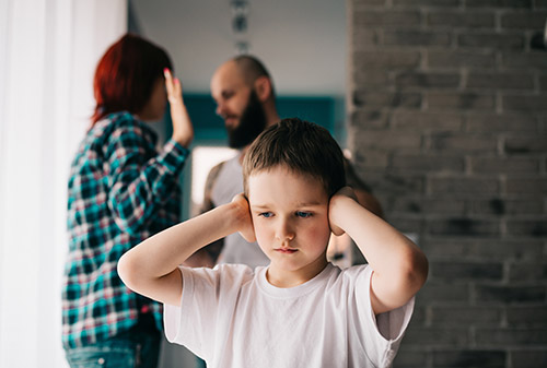 Child covering their ears while parents quarrel