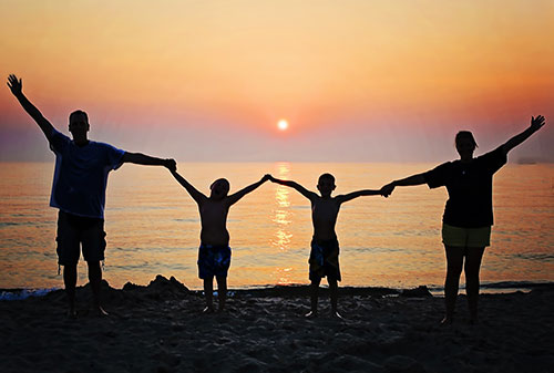 Silhouette of family members holding hands at sunset