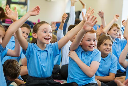 Schoolchildren with their hands up to answer a question
