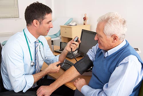 Doctor taking senior man's blood pressure