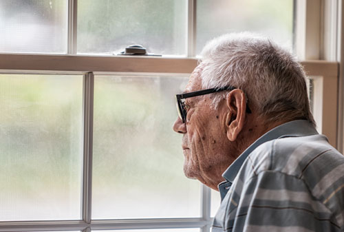 Senior man staring through window