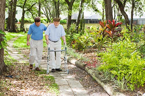 An elderly man taking a walk in the garden with a carer