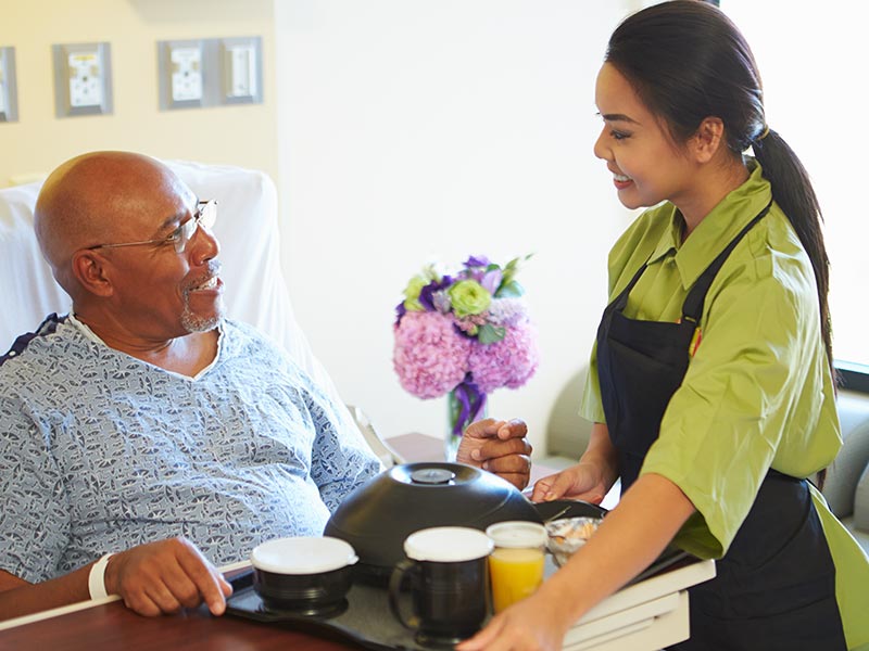 A health and social care worker serving food in hospital