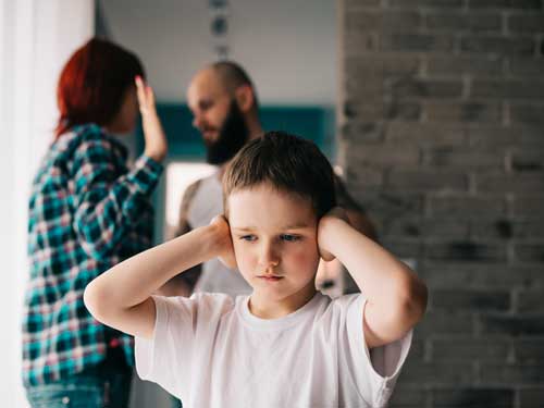 A sad child covering his ears
