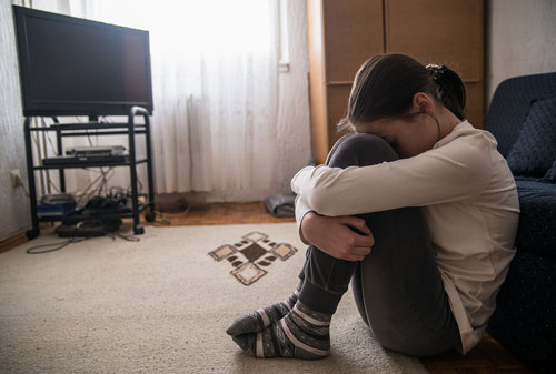 A girl with her head pressed against her knees