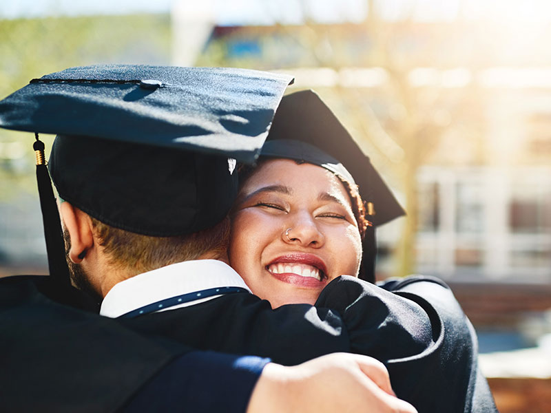 Young adults hugging during graduation ceremony