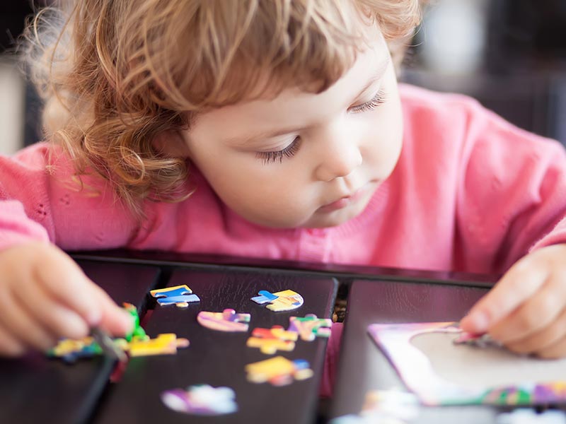 A young child building a jigsaw puzzle