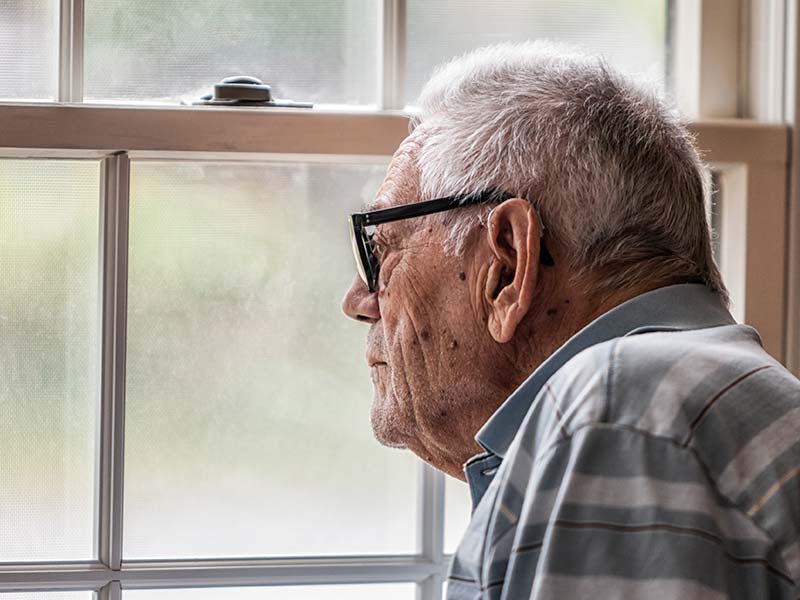 A senior man staring through the window