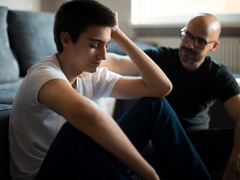 A teenager with their head in their hands