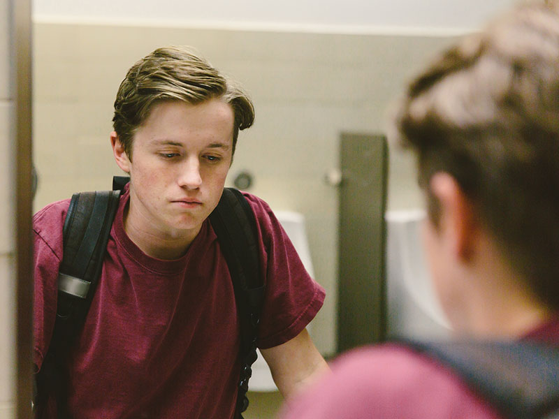 A teenager looking at himself in the mirror