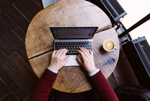 Directly above view of a man working on laptop in coffee shop