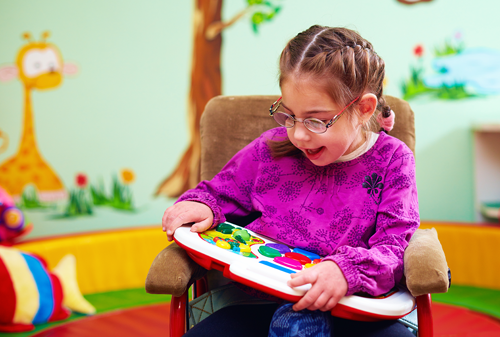 Girl in wheelchair playing with developing toy
