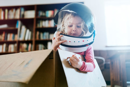 A young girl playing in a cardboard spaceship