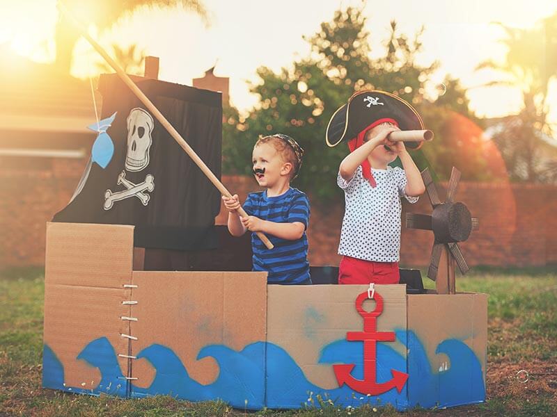 Two boys playing pirates in a cardboard ship