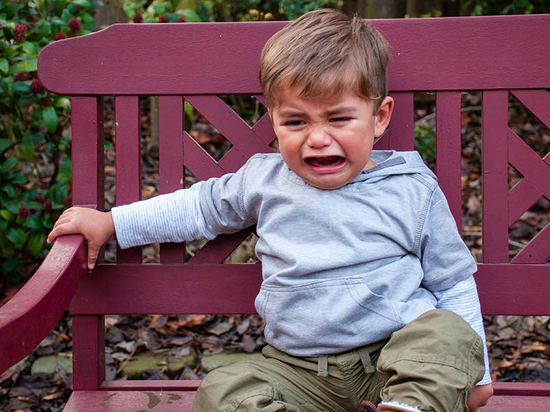A young child sat on a bench, crying