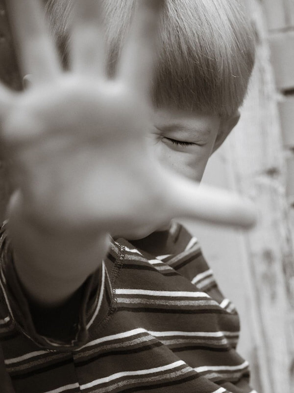 A child with their hand raised as a 'stop' sign